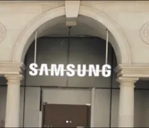 The entrance of a building features a prominently displayed Samsung logo above the doors, framed by elegant columns