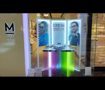 A brightly lit eyewear display featuring colorful panels, framed images of two men, and bold branding