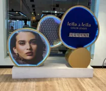 A stylish promotional display featuring a young woman's face alongside colorful circles showcasing 'Leila a Leila Color Lenses'
