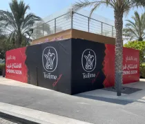 A construction site for 'TeaTime,' with large black and red signage, surrounded by palm trees