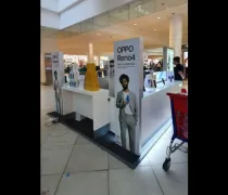 A promotional display for the OPPO Reno4 features large posters in a mall with product showcases and shoppers in the background