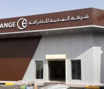 Exterior view of a modern financial services building, featuring a brown and gray facade with Arabic signage above the entrance